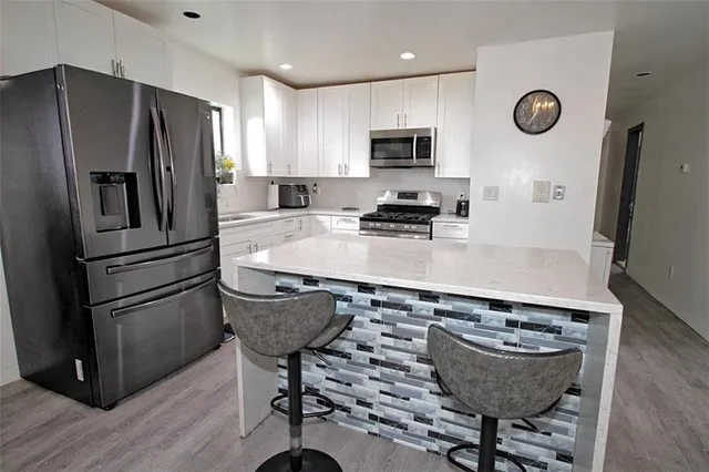 a kitchen with stainless steel appliances granite countertop a sink stove refrigerator and microwave