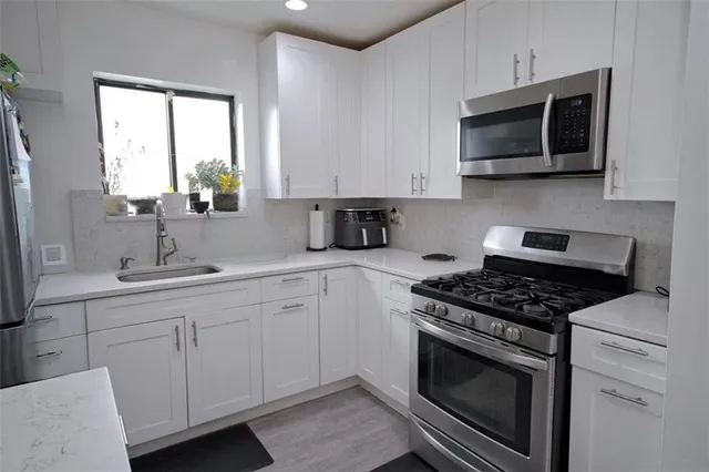 a kitchen with cabinets stainless steel appliances a sink and a window