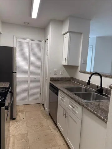 a kitchen with granite countertop a sink stove and refrigerator