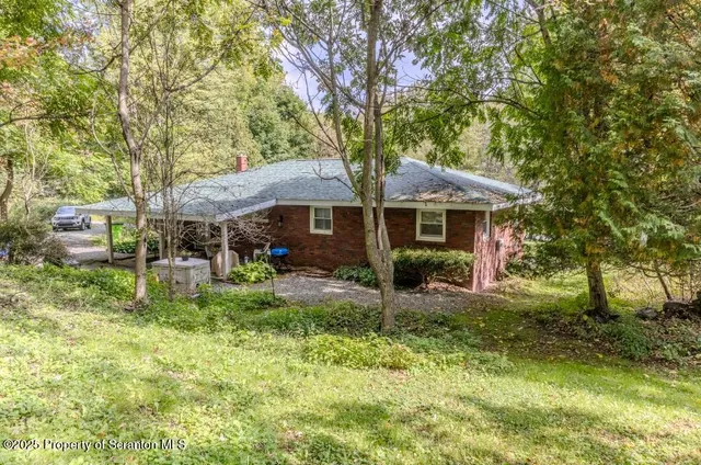 an aerial view of residential house with outdoor space and trees around