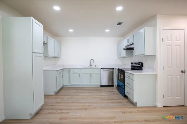 a kitchen with white cabinets stainless steel appliances and sink