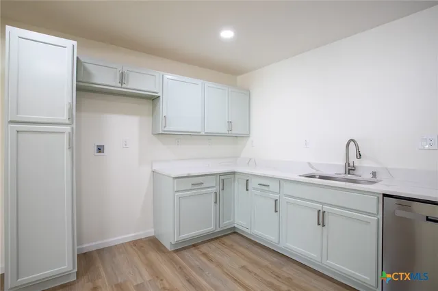 a kitchen with a sink cabinets and wooden floor