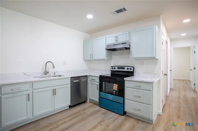 a kitchen with granite countertop a sink stainless steel appliances and cabinets