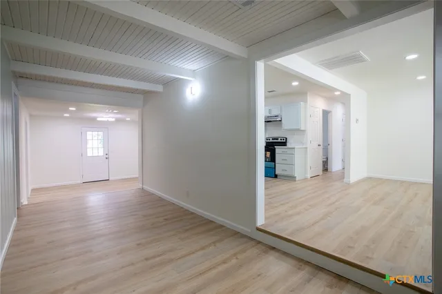 a view of a hallway with wooden floor and a kitchen