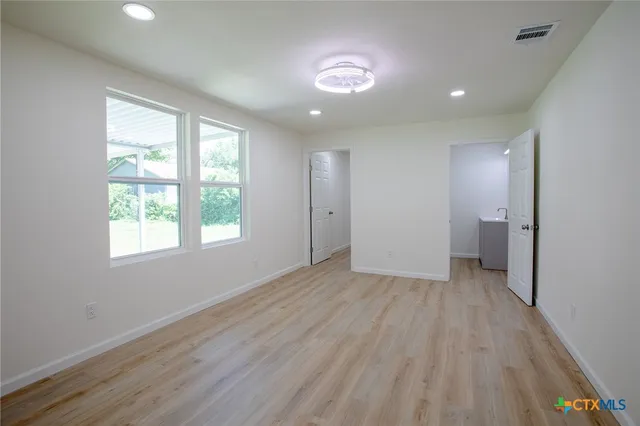 an empty room with wooden floor and windows