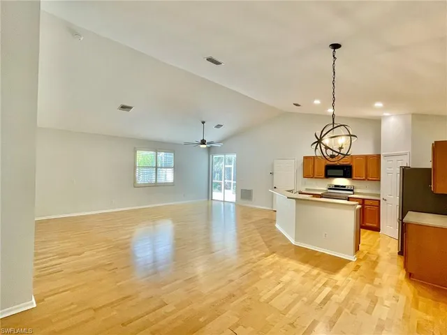 a view of a kitchen with kitchen island a sink stainless steel appliances and cabinets