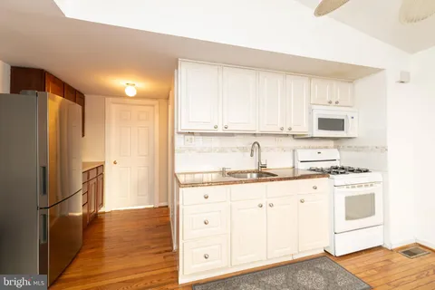 a kitchen with granite countertop white cabinets and refrigerator