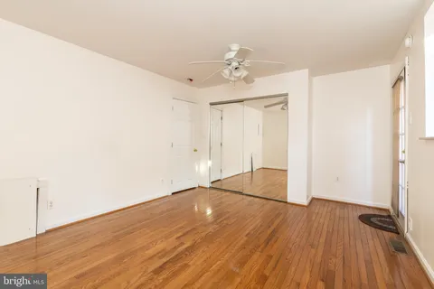 an empty room with wooden floor chandelier fan and windows