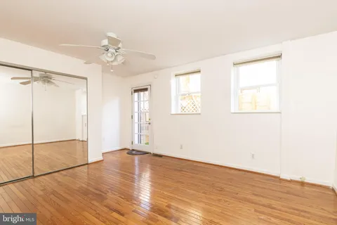 an empty room with wooden floor fan and windows