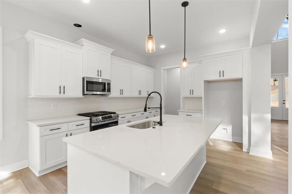 30 Rushden Way Southeast Rome, GA 30161 - Photo 17 of 58 a kitchen with stainless steel appliances a stove a sink a microwave a refrigerator and white cabinets with wooden floor