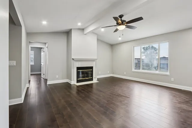 an empty room with wooden floor fireplace and windows