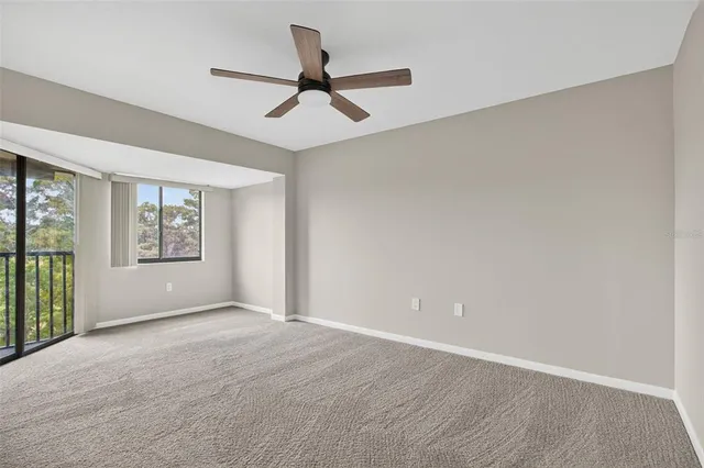 a view of empty room with wooden floor and ceiling fan