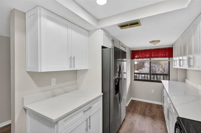 a view of an empty room with wooden floor and a ceiling fan