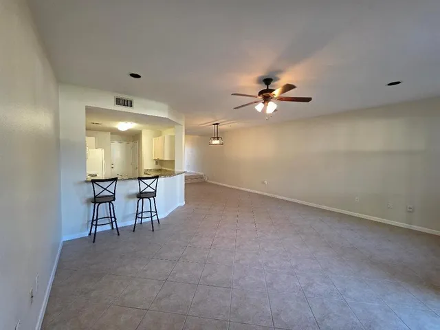 an empty room with chandelier fan and windows