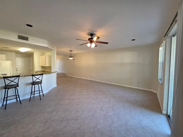 en empty room with windows and ceiling fan