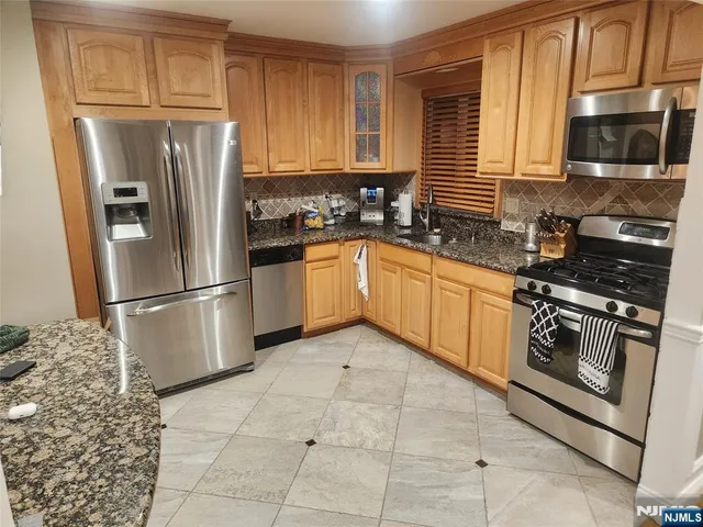 a kitchen with stainless steel appliances granite countertop a refrigerator stove top oven and sink