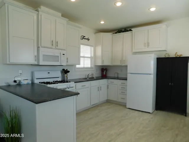a kitchen with granite countertop white cabinets and white appliances