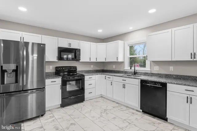 a kitchen with granite countertop white cabinets and a window