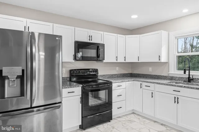 a kitchen with granite countertop a sink and white cabinets