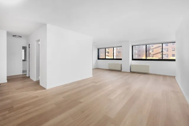 a view of empty room with wooden floor and window