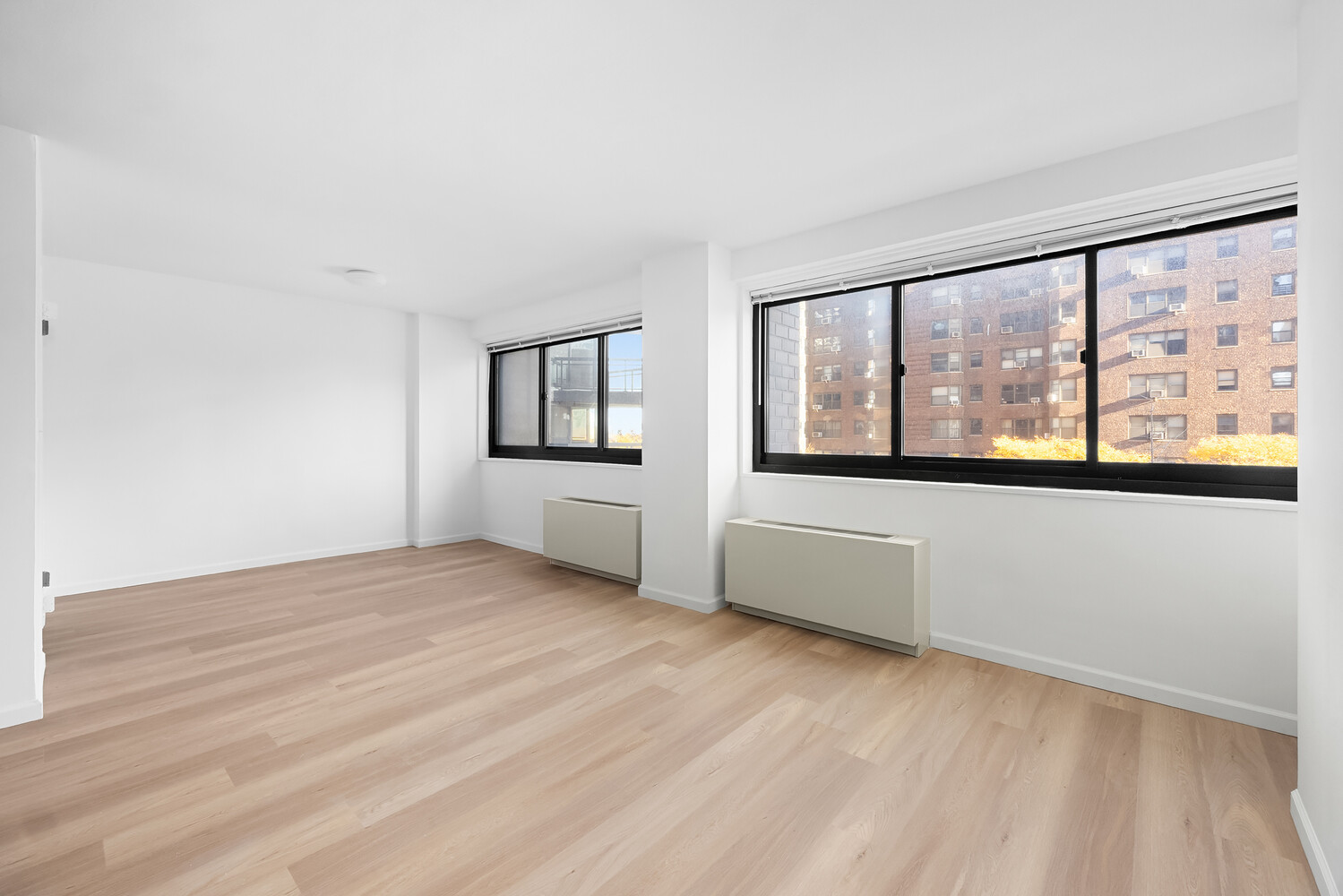 1725 York Avenue, Unit 5E Manhattan, NY 10128 - Photo 4 of 13 an empty room with wooden floor and windows