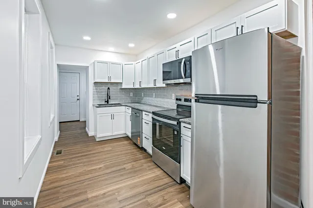 a kitchen with stainless steel appliances a refrigerator sink and white cabinets
