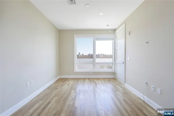 a view of an empty room with a window and wooden floor