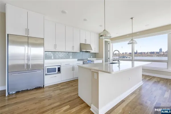 a kitchen with kitchen island granite countertop a sink cabinets and stainless steel appliances