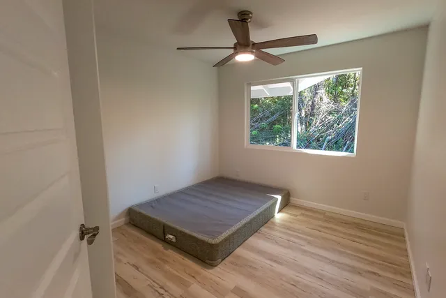 an empty room with wooden floor fan and windows