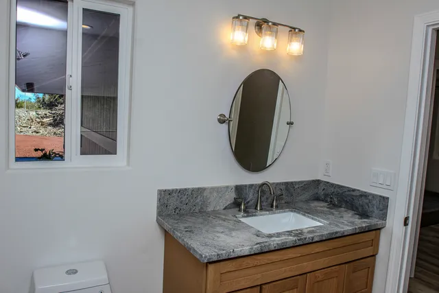 a bathroom with a granite countertop sink and a mirror