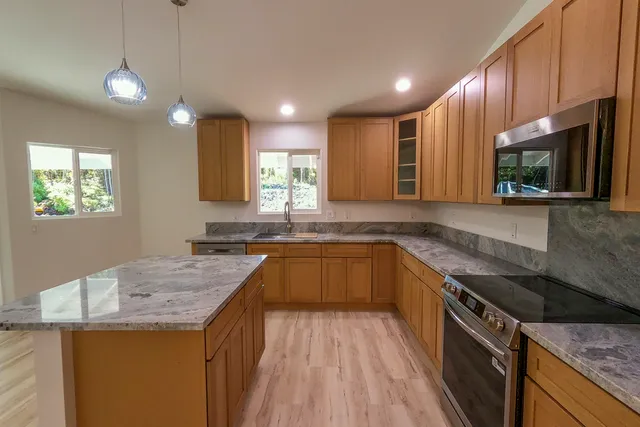 a kitchen with granite countertop a sink a counter space appliances and cabinets