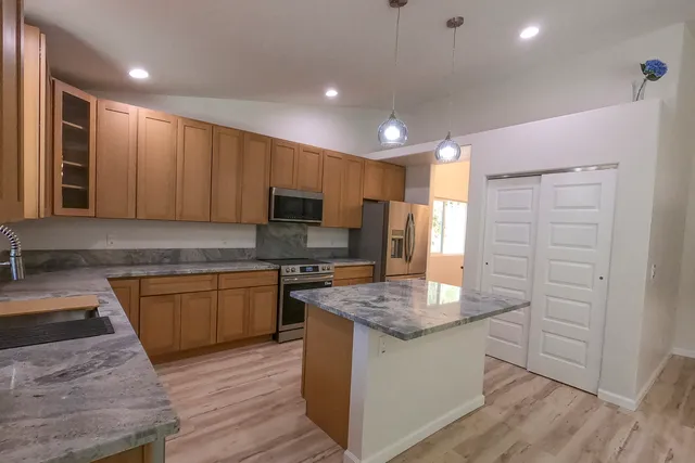 a kitchen with granite countertop cabinets stainless steel appliances a sink and a center island