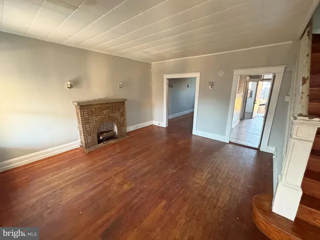 an empty room with wooden floor and fireplace