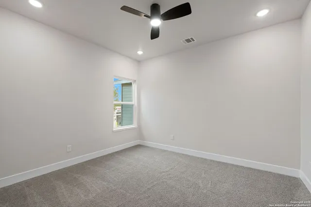 an empty room with windows and ceiling fan