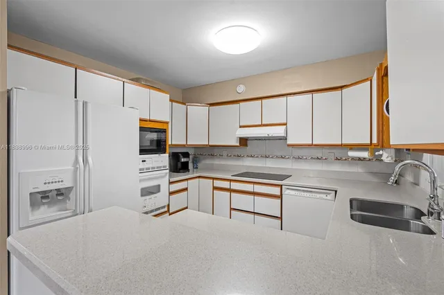 a kitchen with granite countertop a refrigerator sink and cabinets