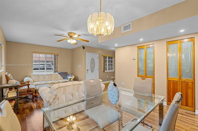 a view of a dining room with furniture a chandelier and large windows