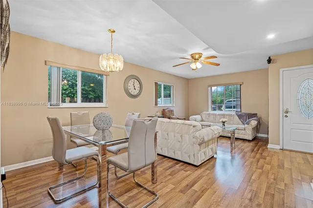 a living room with couches a dining table and a chandelier with wooden floor