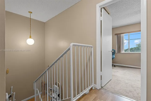 a view of a hallway to a livingroom with wooden floor and staircase
