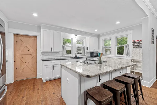a kitchen with granite countertop a stove a sink and a refrigerator