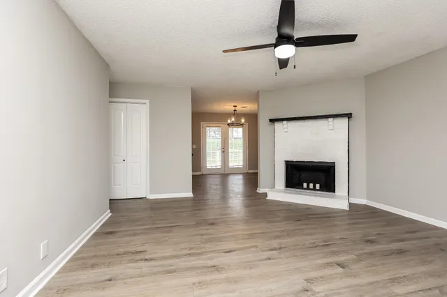a view of an empty room with wooden floor fireplace and a window