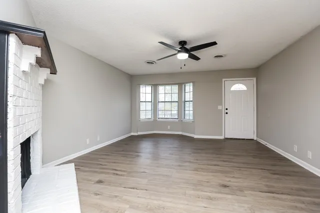 a view of an empty room with a window and wooden floor
