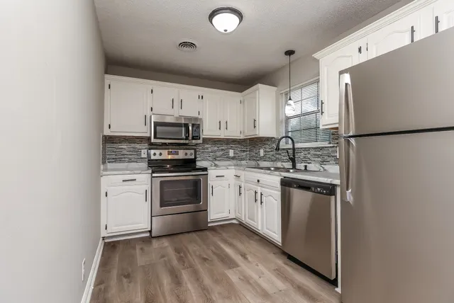 a kitchen with granite countertop a refrigerator stove a sink dishwasher and a stove