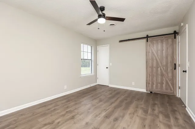 an empty room with wooden floor cabinet and windows