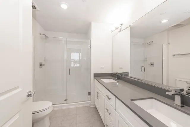 a spacious bathroom with a granite countertop sink a toilet a mirror and shower