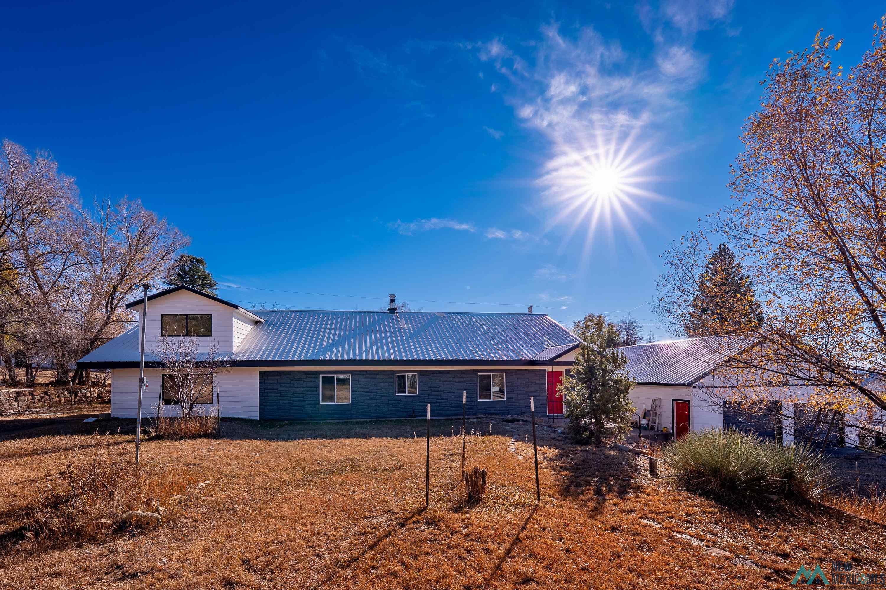 1131 Lincoln Avenue Raton, NM 87740 - Photo 2 of 41 Rear view of property featuring a metal roof and a yard