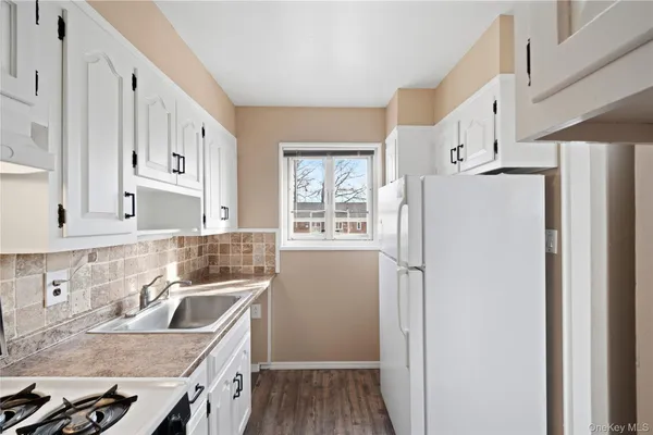 a kitchen with stainless steel appliances granite countertop a refrigerator a sink dishwasher a stove and white countertops with wooden floor