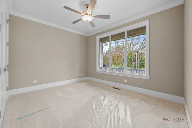 an empty room with chandelier fan and windows