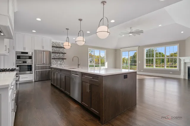 a large white kitchen with a large island oven a stove with wooden floors