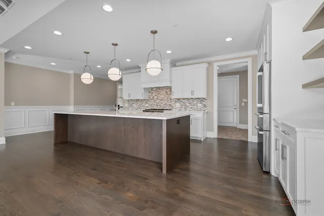 a large kitchen with kitchen island a large counter top stainless steel appliances and cabinets