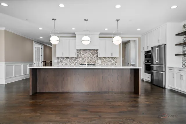 a large kitchen with granite countertop a stove a sink and a wooden floors